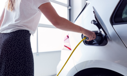 woman using ev charging station in garage